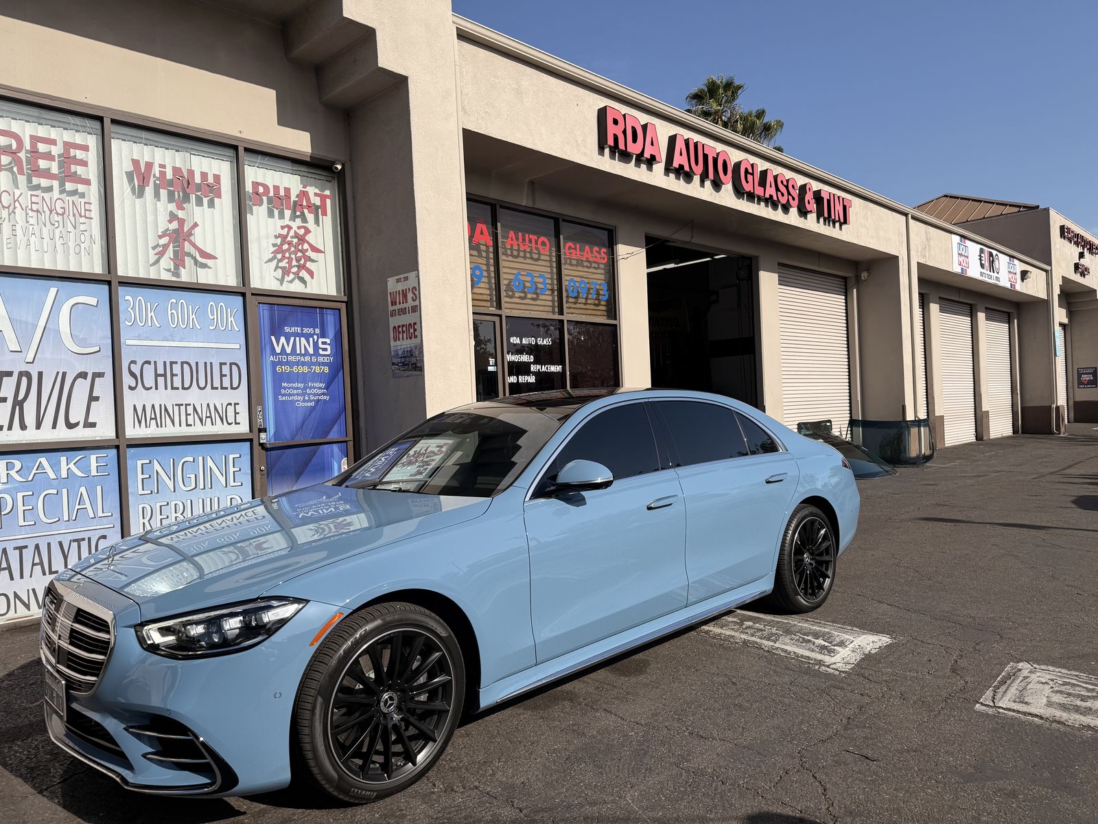 Light blue Mercedes in front of the storefront